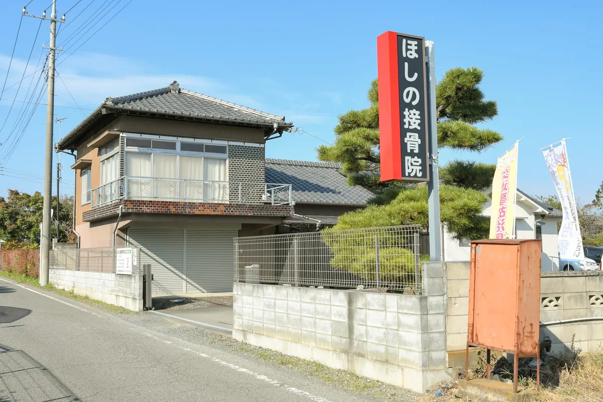 道路沿いに立つ「ほしの接骨院」の赤い看板