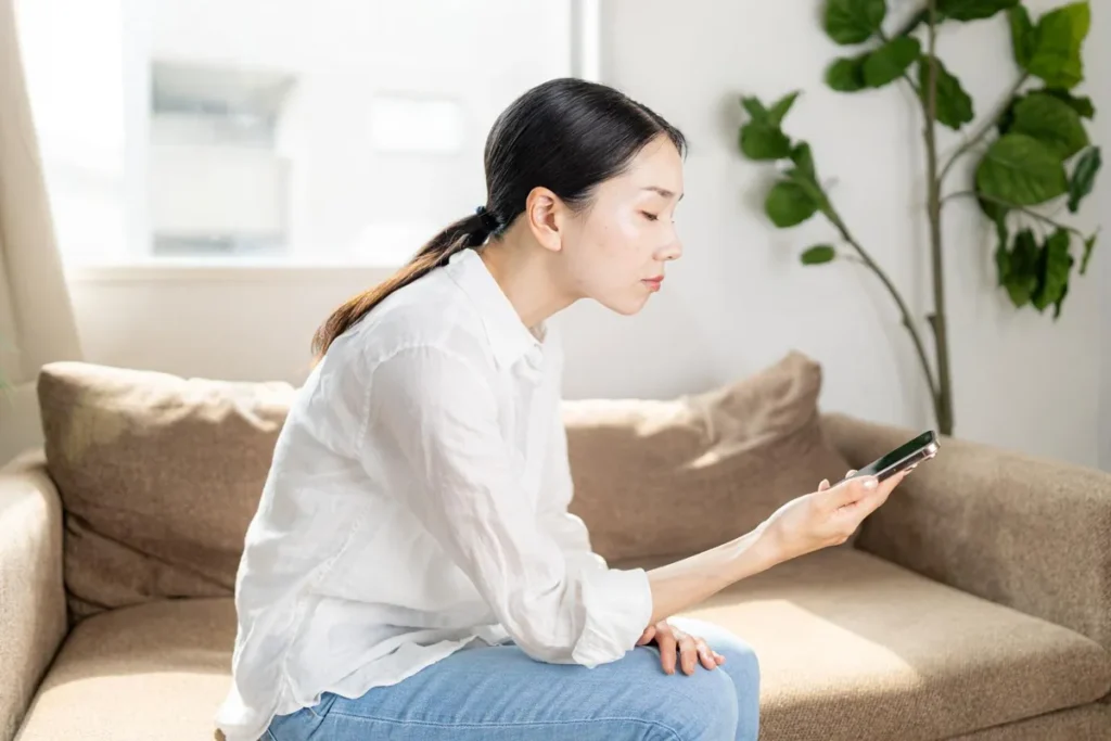 ソファでスマートフォンを見る女性