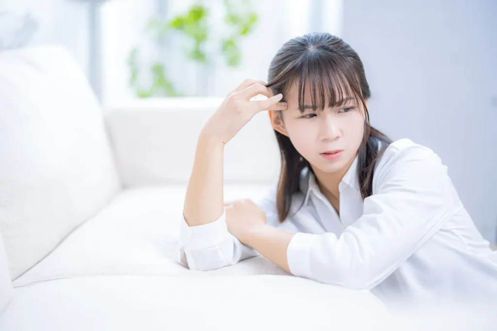 育児ストレスで頭痛に苦しみソファーにもたれかかる女性
