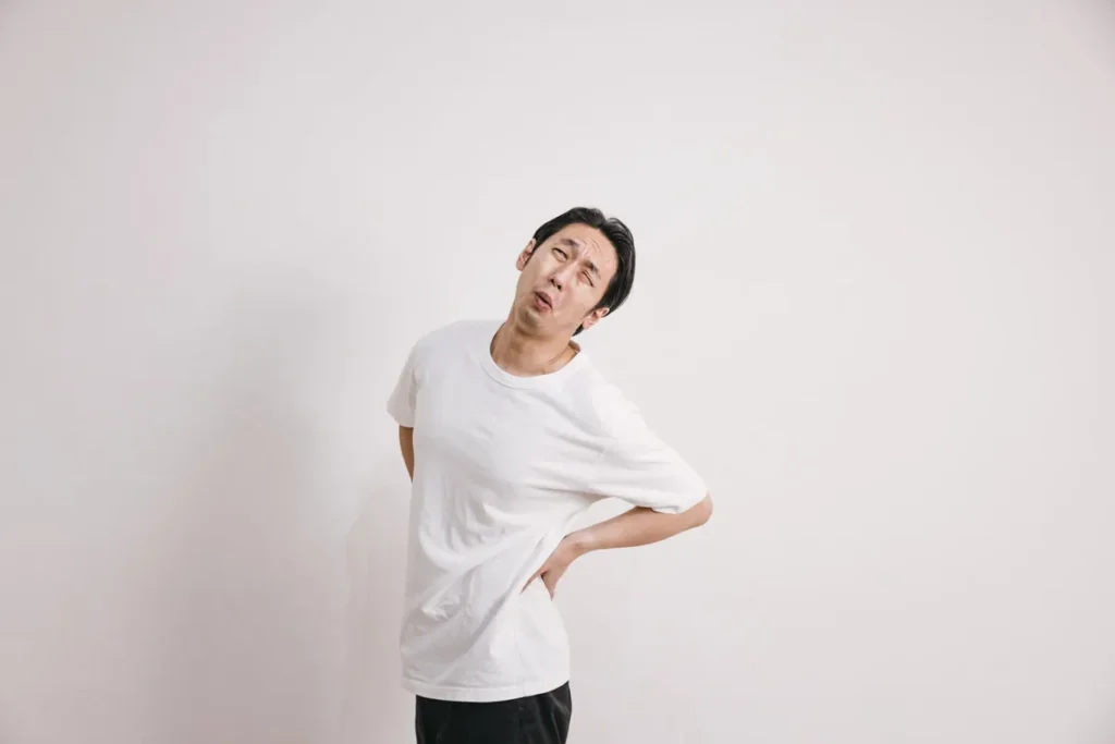 腰を押さえて痛みを訴えるぎっくり腰の男性