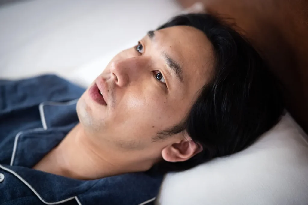 不眠で目覚めた男性がベッドで天井を見つめる